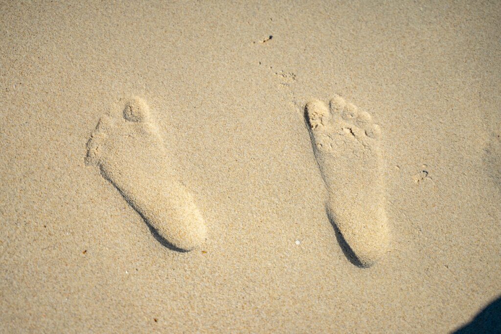 Close-up of two footprints in sandy beach, capturing a sense of adventure.